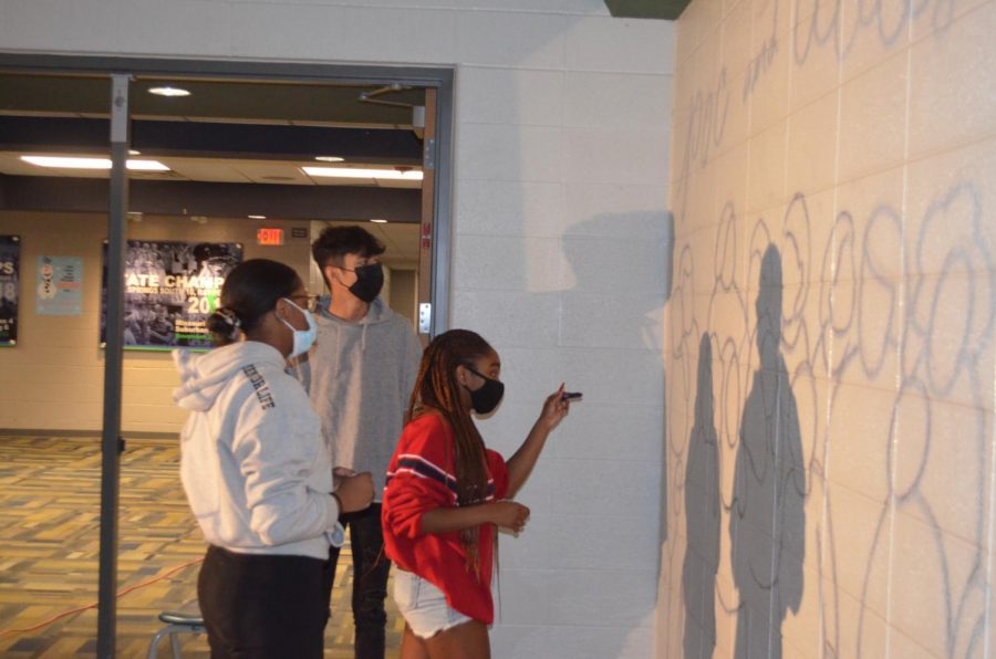 From left, South seniors MacKenzie Hammonds, Zain Mohammad, and Anaya Dewey work on a mural outside of the main gym. The three seniors are members of the People of Color and Allies club at South.